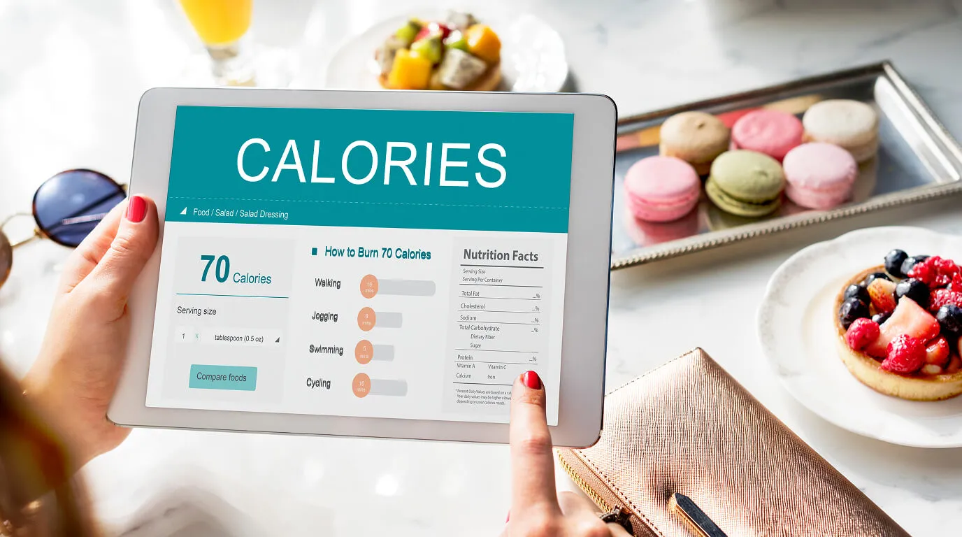 Food on a kitchen scale and a phone with a macro tracking app